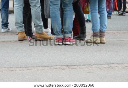 Young people on the street - slightly blurred image. Urban group of youngsters in a city. Youth gathering together in metropolitan area. Teens hanging around. Young adults.