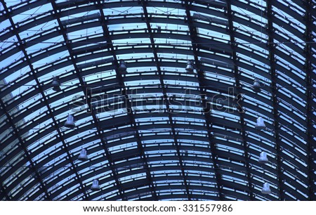 Glass roof of major railway station in blue shade. Arching dome ceiling of train station. European architecture in Germany. Blue tinted glass roof. Metal supporting structure. Windows towards sky.