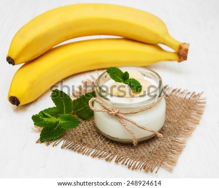Banana with natural yogurt on a old white wooden background