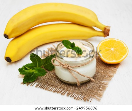 Banana with natural yogurt on a old white wooden background