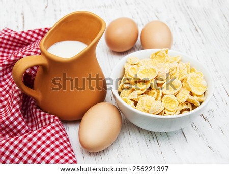 Cornflakes with milk and eggs on a wooden background