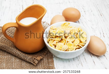 Cornflakes with milk and eggs on a wooden background