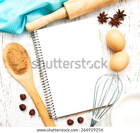 blank recipe book with baking ingredients on a old wooden background