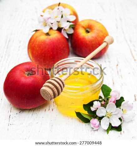 Apples with honey and apple tree flowers on a wooden background