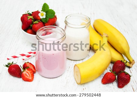 Bananas  and strawberries with yogurt on a wooden background