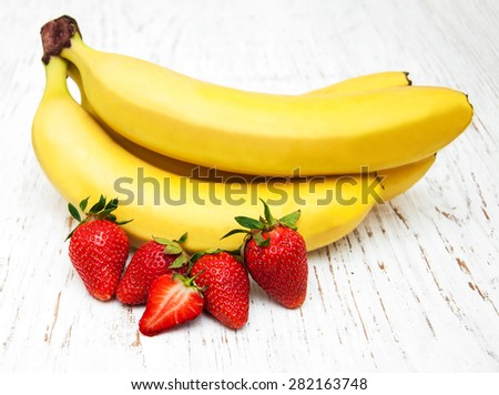 Bananas and strawberries on a old wooden background