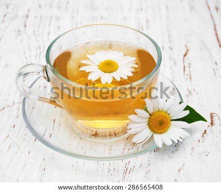 Cup of herbal tea with chamomile on a old wooden background