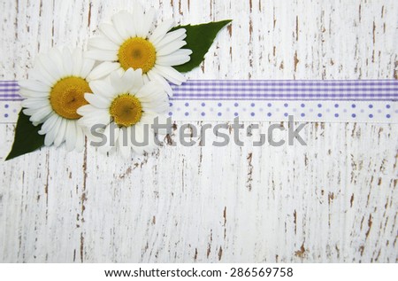 Wooden background with chamomile flowers and ribbon