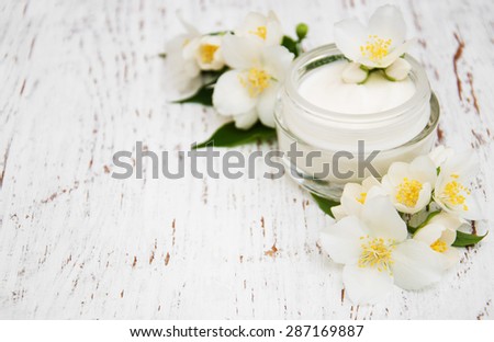 face and body cream moisturizers with jasmine flowers on white wooden background