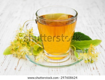 Cup of herbal tea with linden flowers on a old wooden background