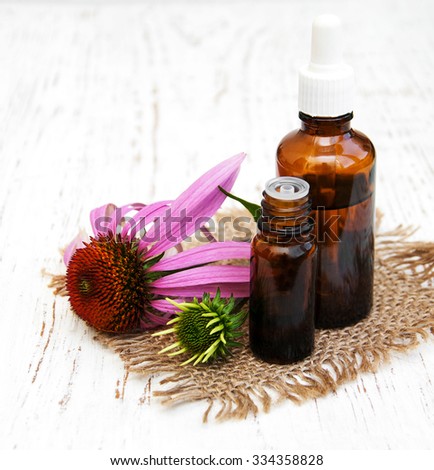 bottles with essence oil with purple echinacea on a wooden background