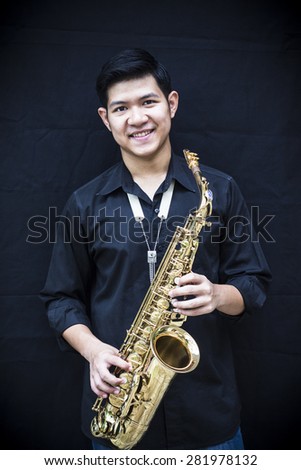CHIANGMAI, THAILAND - MAY 28, 2015.  image of a handsome young man smiling while holding his  alto saxophone made  in France by selmer company at In  Grace Church Chiangmai, Thailand
