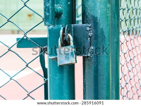 green master key locked on the basket ball stadium gate , green metal fence
