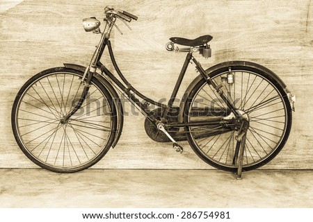 Classic vintage bicycle on concrete floor with wooden background, vintage style