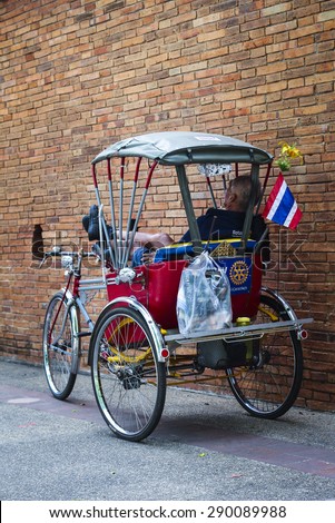 CHIANGMAI, THAILAND - JUNE 23,2015. image of the old man sleeping in his tricycle with Thailand flag on the tricycle  beside the red brick wall in old city, Chiangma, i Thailand