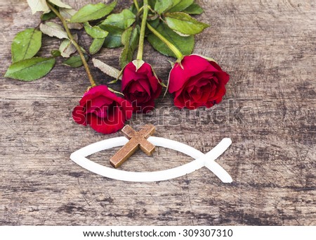The  wooden  cross  over the white christian fish and red roses  on wooden background, world mission concept.