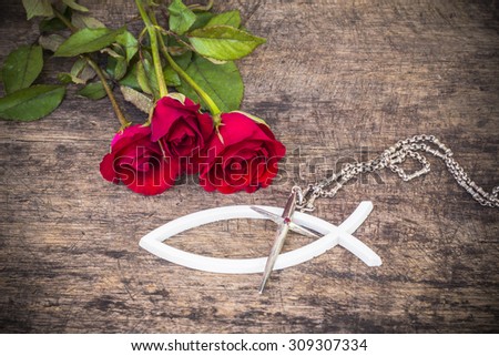The metal cross  over the white christian fish and with red roses  on wooden background, world mission concept.