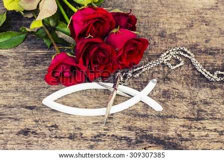 The  metal  cross  over the white christian fish and with red roses  on wooden background, world mission concept.