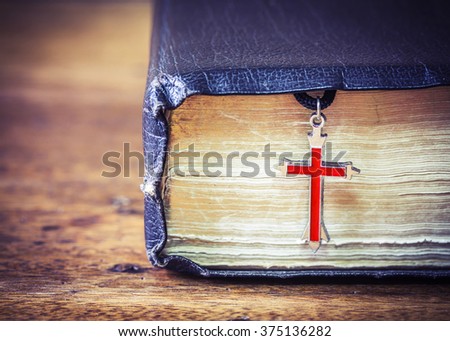 The old holy bible with  metal res cross on wooden background