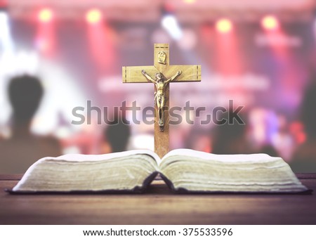 Christian worship, wooden cross with crucifix of Jesus Christ with burred image of people in music concert, focus on the crucifix, Christian concept of worship