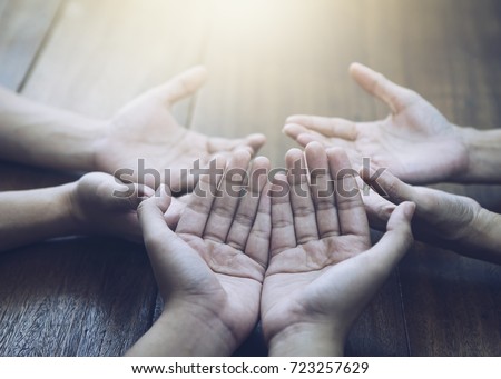 Three people pray and praising God together over wooden table with the light from above, copy space.