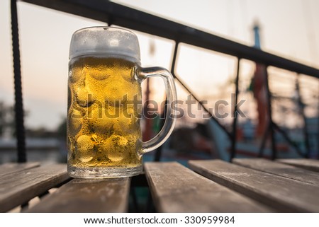 Draught Beer with fisherman boat backgroung in the evening time (Selective focus point)