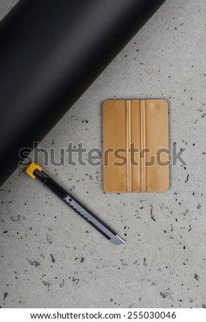 gold squeegee and knife with black mate foil on concrete floor
