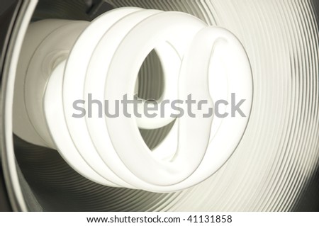 Energy saving compact fluorescent bulb glowing inside a round metal dish