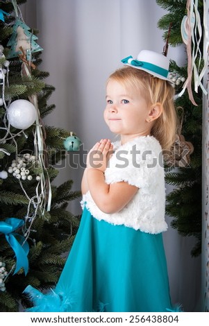 little girl makes a wish for the new year near Christmas trees