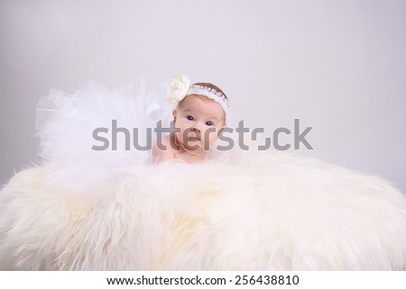 funny little girl in a white skirt, and a pack with a white bandage on his head lies on fur
