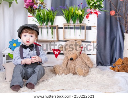 funny cute little boy with a cap on his head and a pencil mustache sitting on spring background and committed looks in the picture