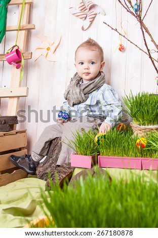 Beautiful funny little boy playing among easter spring scenery. Studio filming a child in a bright, juicy spring location. Child is happy and cheerful.