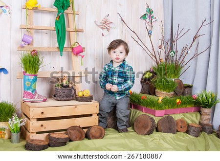 Beautiful funny little boy playing among easter spring scenery. Studio filming a child in a bright, juicy spring location. Child is happy and cheerful.