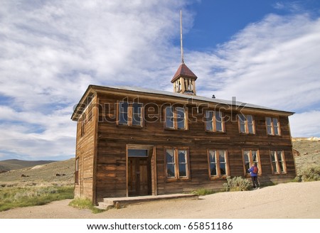 Tourist peering into the windows of Bodie Schoolhouse, Bodie Ghost Town, CA