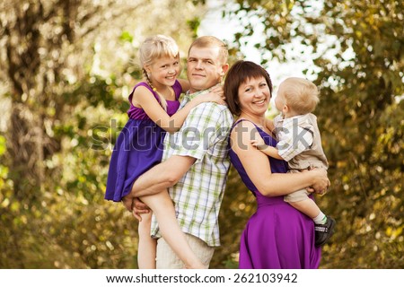 Father, mother, daughter and son walking in the countryside. Parents and children are dressed in the same clothes. Happy young family