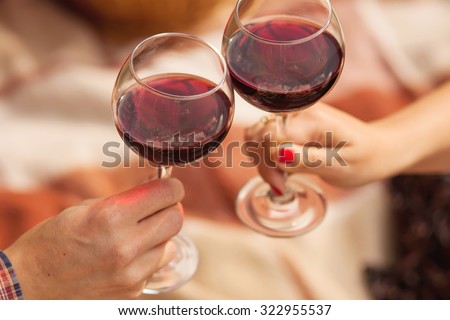 Man and woman drinking red wine. In the picture, close-up hands with glasses. They are celebrating their wedding anniversary.