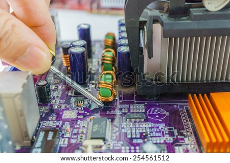 close up technician\'s hands fixing computer main-board with screwdriver
