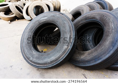 Tires stacked near cement wall, used car tires