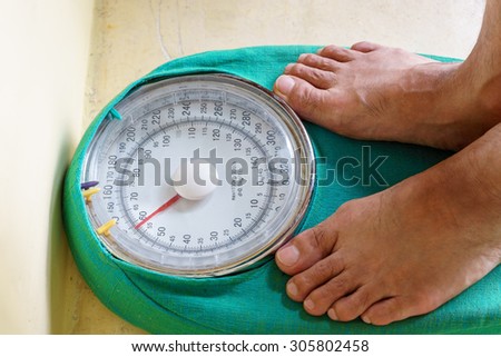 Man\'s feet standing on weighing machine, weighing scale