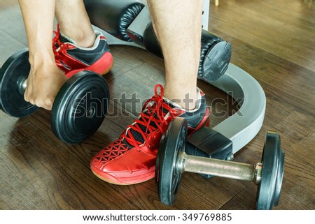 Hand is holding dumbbells on wood floor in fitness gym, Weight Exercise Equipment