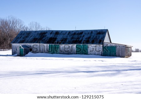Barn in a field in winter, with a beautiful blue sky.