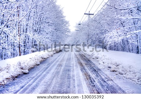 Winter Road in Snowy forest in blue tone with electric post.