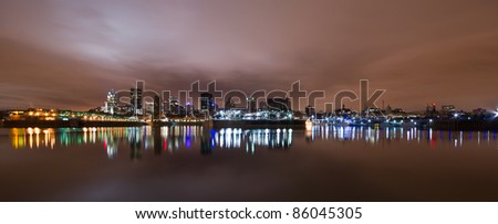 Wide Panoramic View of Montreal at night with color light reflection in water.