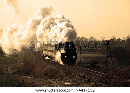 Vintage steam train passing through countryside, wintertime