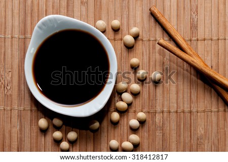 A bowl of soy sauce, soy grains and chopsticks