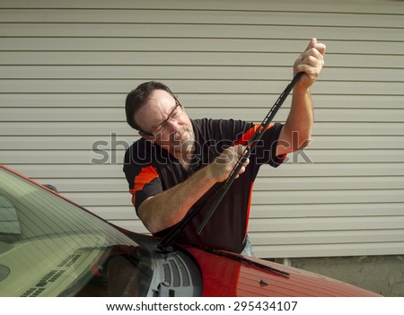 Mechanic changing windshield wiper blades on a car.