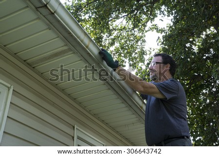 Cleaning gutters of leaves and sticks on a home.