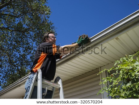 Worker cleaning gutters on a customers home.