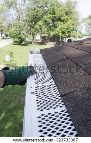 Contractor checking installation of plastic leaf guards on a customers gutter.