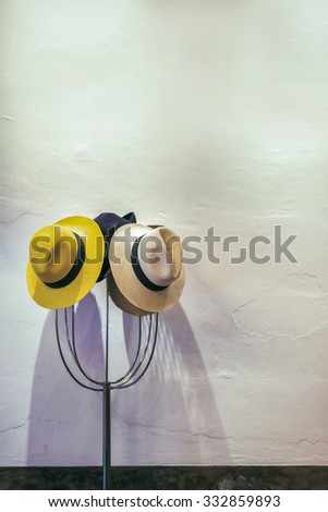 Hats on hanger, white wall background, selective focus.